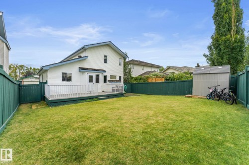 Expansive backyard featuring a manicured lawn, a spacious deck with railing, a detached storage shed, and a tall privacy fence - 362 Blackburn Drive E, Edmonton, AB - Outdoor
