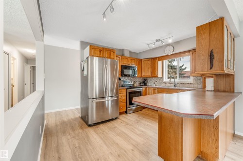 The kitchen features wood cabinetry, stainless steel appliances, and a window above the sink - 2437 89 Street, Edmonton, AB - Indoor Photo Showing Kitchen