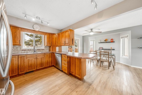 The kitchen features wood cabinetry, stainless steel appliances, and a tiled backsplash - 2437 89 Street, Edmonton, AB - Indoor