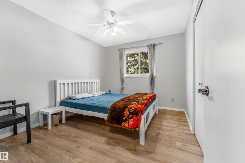 This room features light-colored walls, wood-style flooring, a window providing natural light, and a ceiling fan - 2437 89 Street, Edmonton, AB - Indoor Photo Showing Bedroom