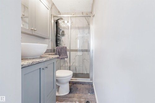 The bathroom features a vessel sink set on a vanity with gray cabinetry and a patterned countertop - 2437 89 Street, Edmonton, AB - Indoor Photo Showing Bathroom