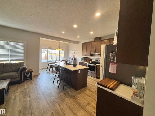 Open-concept living space featuring wood-finish flooring, recessed lighting, and a kitchen island with seating - 11 James Crescent, St. Albert, AB - Indoor