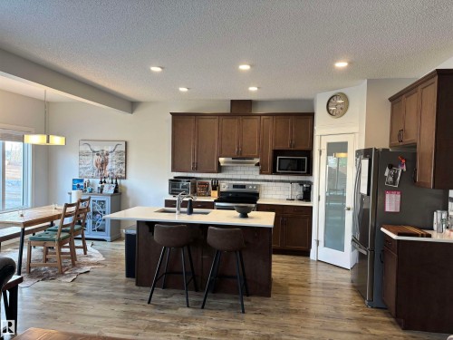 Open-concept kitchen featuring wood-finish flooring, recessed lighting, and a kitchen island with seating - 11 James Crescent, St. Albert, AB - Indoor Photo Showing Kitchen