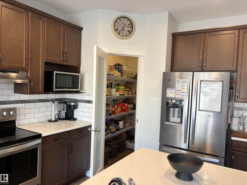 Well-appointed kitchen featuring rich wood-finish cabinetry, a subway tile backsplash, and light-toned countertops - 11 James Crescent, St. Albert, AB - Indoor Photo Showing Kitchen