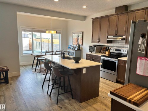 Open-concept kitchen featuring an island with seating, light wood-finish flooring, recessed lighting, and stainless steel appliances - 11 James Crescent, St. Albert, AB - Indoor Photo Showing Kitchen