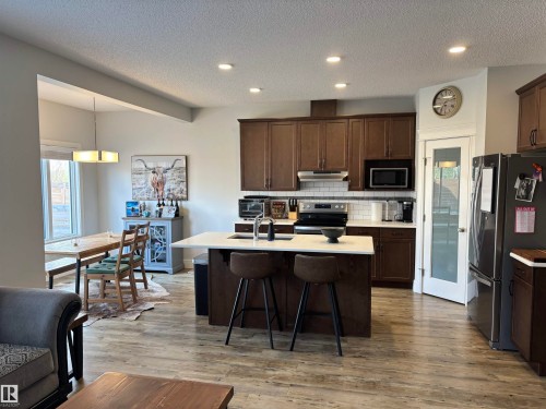 Open-concept kitchen and dining area featuring wood-finish flooring, recessed lighting, and a kitchen island with a light-toned countertop - 11 James Crescent, St. Albert, AB - Indoor Photo Showing Kitchen