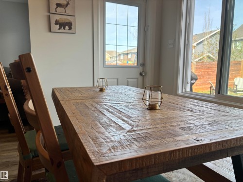 Expansive wood-finish dining table with visible grain details, accompanied by a wood-frame dining chair - 11 James Crescent, St. Albert, AB - Indoor