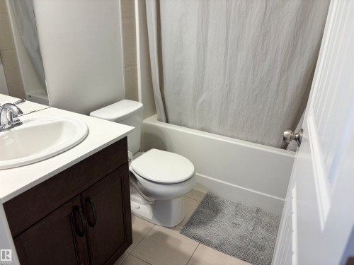 Bathroom featuring a white porcelain sink, dark wood-finish vanity with dual doors, white countertop, toilet, and a white bathtub with shower - 11 James Crescent, St. Albert, AB - Indoor Photo Showing Bathroom
