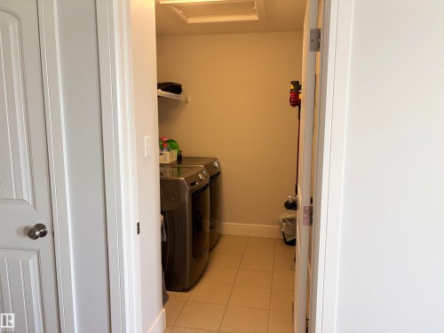 Dedicated laundry alcove featuring tile flooring, built-in shelving, and a prominent washer and dryer - 11 James Crescent, St. Albert, AB - Indoor Photo Showing Laundry Room