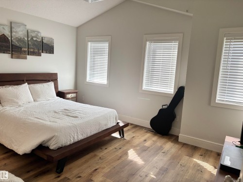 Vaulted ceiling room featuring wood-finish flooring, multiple windows with blinds, and a built-in ceiling vent - 11 James Crescent, St. Albert, AB - Indoor Photo Showing Bedroom