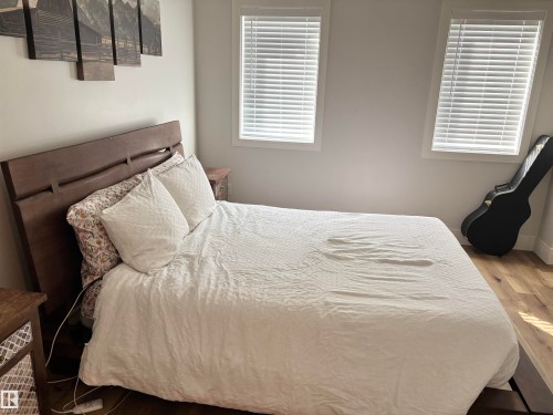 Bright room featuring dual windows with blinds, light-toned wall paint, and wood-finish flooring - 11 James Crescent, St. Albert, AB - Indoor Photo Showing Bedroom