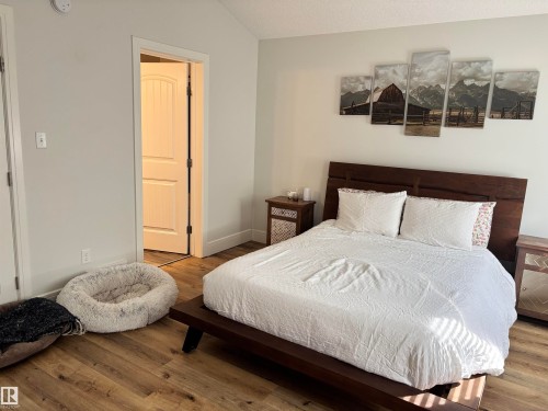 Bedroom featuring vaulted ceilings, wood-finish flooring, and light-toned wall paint - 11 James Crescent, St. Albert, AB - Indoor Photo Showing Bedroom