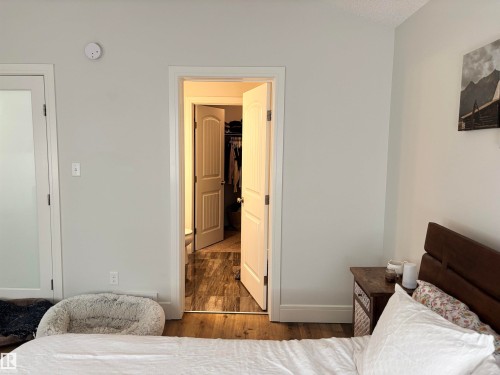 Bedroom featuring wood-finish flooring, a white paneled door, and a frosted glass door - 11 James Crescent, St. Albert, AB - Indoor Photo Showing Bedroom