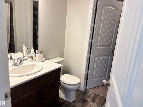Vanity featuring an integrated sink with chrome faucet, a white countertop, and dark wood-finish cabinetry - 11 James Crescent, St. Albert, AB - Indoor Photo Showing Bathroom