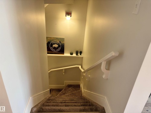 Carpeted staircase with white painted handrail, recessed wall shelf, and built-in wall sconce lighting - 11 James Crescent, St. Albert, AB - Indoor Photo Showing Other Room