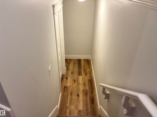 Hardwood-finish flooring extending into a doorway with white trim - 11 James Crescent, St. Albert, AB - Indoor Photo Showing Other Room