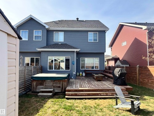 Rear exterior featuring blue horizontal siding, a multi-level wood deck, an integrated hot tub, and sliding glass doors - 11 James Crescent, St. Albert, AB - Outdoor With Exterior