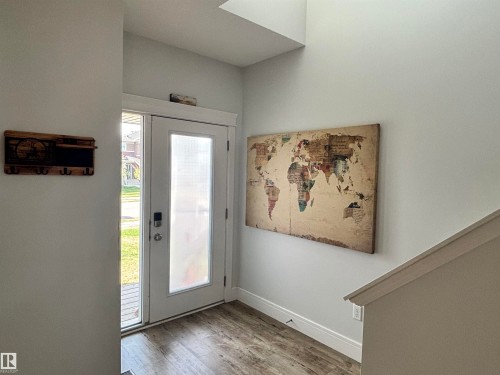 Entryway featuring wood-finish flooring, a white paneled door with frosted glass, and a white staircase with a matching handrail - 11 James Crescent, St. Albert, AB - Indoor Photo Showing Other Room