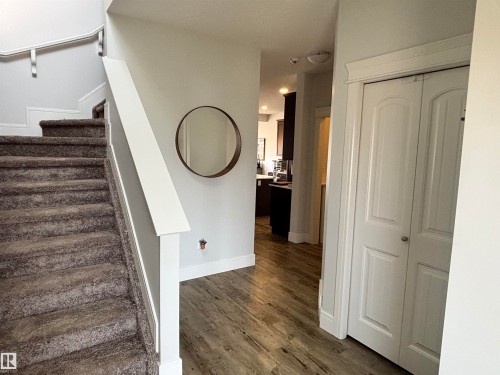 Entryway featuring wood-finish flooring, a carpeted staircase with white trim, and a bi-fold closet door with panel detailing - 11 James Crescent, St. Albert, AB - Indoor Photo Showing Other Room