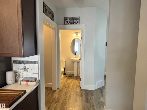 Hallway featuring wood-finish flooring, white baseboards, and a bright interior - 11 James Crescent, St. Albert, AB - Indoor Photo Showing Kitchen