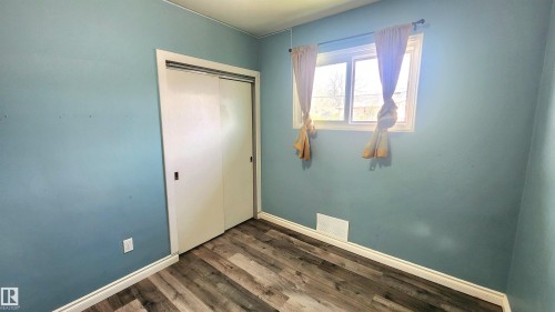 Bedroom featuring wood-finish flooring, white baseboards, a window with white trim, and a closet with sliding panel doors - 12139 81 Street, Edmonton, AB - Indoor Photo Showing Other Room