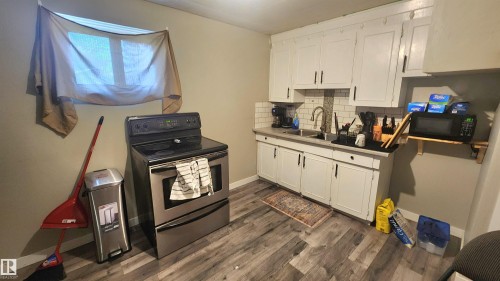 Kitchen featuring white cabinetry, subway tile backsplash, a stainless steel range, and wood-finish flooring - 12139 81 Street, Edmonton, AB - Indoor Photo Showing Kitchen With Double Sink
