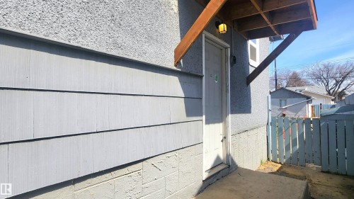 Exterior entry featuring a wood-framed overhead awning and an attached outdoor light fixture - 12139 81 Street, Edmonton, AB - Outdoor With Exterior