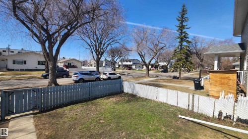 Front yard featuring a small lawn area with a light-colored picket fence and a concrete sidewalk - 12139 81 Street, Edmonton, AB - Outdoor