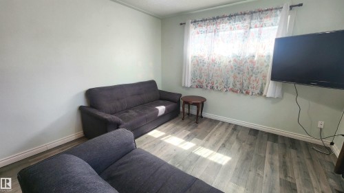 Room featuring wood-finish flooring, light-colored walls, and a window with white trim - 12139 81 Street, Edmonton, AB - Indoor