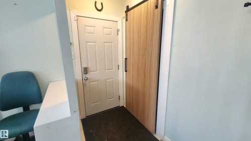 Entryway featuring a paneled door with integrated smart lock, wood-finish sliding barn door, and light-toned wall paint - 12139 81 Street, Edmonton, AB - Indoor Photo Showing Other Room