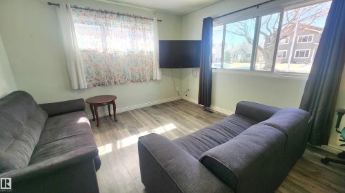 Bright living area featuring wood-finish flooring, light-toned walls, and white trim - 12139 81 Street, Edmonton, AB - Indoor