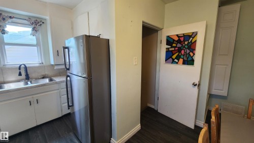 Kitchen area featuring a stainless steel refrigerator, white cabinetry, and a double basin sink with a gooseneck faucet - 12139 81 Street, Edmonton, AB - Indoor Photo Showing Kitchen With Double Sink
