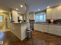 Kitchen featuring wood-finish flooring, recessed lighting, white cabinetry, and a bay window - 