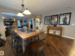 Open-concept living area featuring rich wood-finish flooring, a contemporary overhead light fixture, and neutral wall tones - 