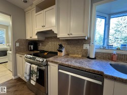 Kitchen with light-toned cabinetry, a mosaic tile backsplash, and a bay window - 