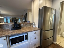Stainless steel French door refrigerator with bottom freezer drawers, built-in microwave, and light-toned cabinetry - 