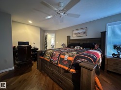 Spacious room featuring wood-finish flooring, a ceiling fan with integrated lighting, a large window with horizontal blinds, and a built-in recessed light fixture - 