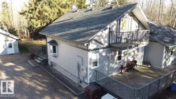 Exterior featuring light gray siding, dark gray roofing, a spacious wood deck, and an upper-level balcony - 