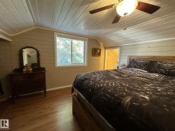 Vaulted ceiling with wood paneling, wood-finish flooring, and a ceiling fan with light fixture - 
