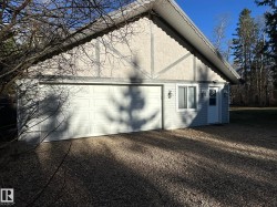 Exterior building featuring a single garage door, light-colored stucco and siding, a side entry door, and exterior lighting fixtures - 