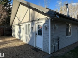Exterior featuring light gray siding, white trim, and a prominent gable with stucco and dark timber accents - 