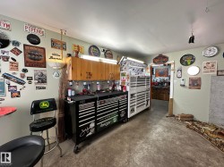 Dedicated workshop space featuring a concrete floor, light-colored walls, and a built-in overhead wooden cabinet - 