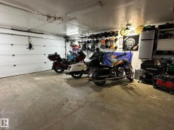 Attached garage featuring a white sectional overhead door, concrete flooring, and fluorescent overhead lighting - 