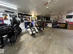 Spacious garage featuring a concrete floor, overhead fluorescent lighting, and extensive wall-mounted storage options - 