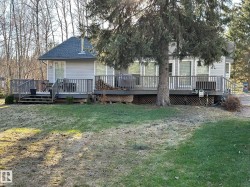 Expansive rear deck featuring multiple access points, gray composite railing, and lattice skirting, overlooking a spacious lawn - 