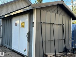 Exterior storage building featuring vertical siding, a white double-door entrance, and a dark-toned gable roof - 