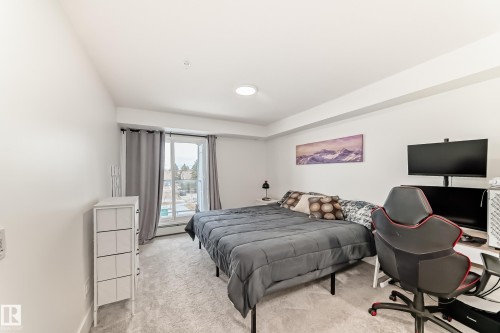 This bedroom features white walls, light-colored carpeting, and a window with curtains - 307 9504 182 Street Nw, Edmonton, AB - Indoor Photo Showing Bedroom