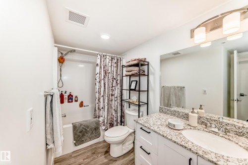 The bathroom features a vanity with a granite countertop, an undermount sink, and a large mirror - 307 9504 182 Street Nw, Edmonton, AB - Indoor Photo Showing Bathroom