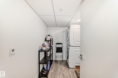 Dedicated laundry area featuring modern stacked appliances, durable flooring, and a white drop ceiling - 307 9504 182 Street Nw, Edmonton, AB - Indoor Photo Showing Other Room