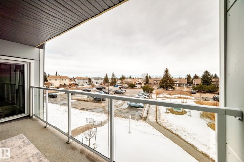 The property features a private balcony with a glass railing, providing an open view of the surrounding residential area and trees - 307 9504 182 Street Nw, Edmonton, AB - Outdoor With Balcony With Exterior